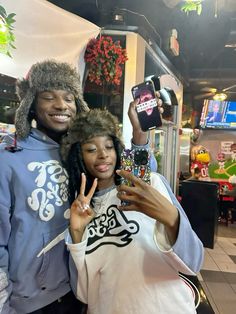 a man and woman posing for a photo in front of a store with their cell phones