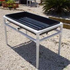 a black tray sitting on top of a white table in the middle of some gravel