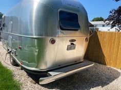 an airstream parked next to a wooden fence