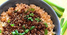 a bowl filled with rice, meat and green onions