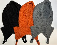 three knitted hats and one crochet hat are lined up on a white surface