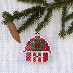 a christmas ornament hanging from a pine tree with a red barn on it