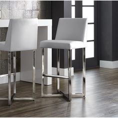 two white bar stools sitting in front of a mirror on a wooden floor next to a wall