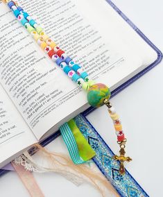 an open book with beads and a cross on it