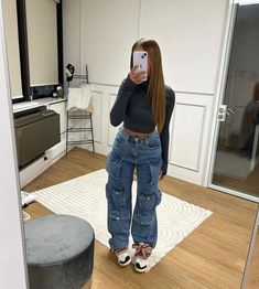 a woman taking a selfie with her cell phone in a room that has white walls and wood floors