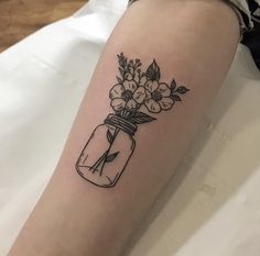 a woman's leg with a tattoo on it that has flowers in a mason jar