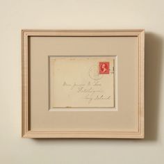 an old postcard with a red stamp on it is hung in a white frame