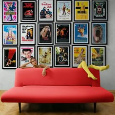 a red couch sitting in front of a wall with posters on it