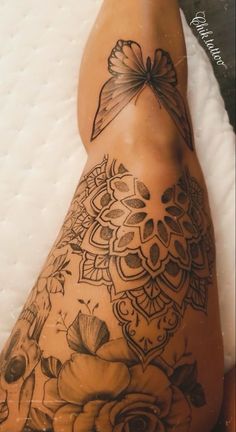 a woman's legs with tattoos on them and flowers in the middle of her leg