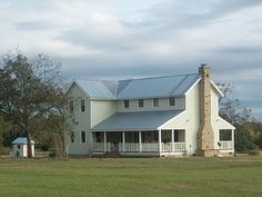 a large white house sitting on top of a lush green field