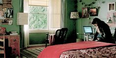 a woman sitting on top of a bed next to a desk with a laptop computer