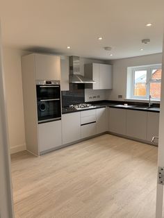 an empty kitchen with white cabinets and black counter tops is seen from the doorway to the living room