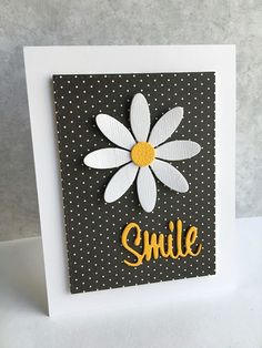 a black and white card with a yellow daisy on it that says smile in gold lettering