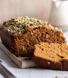 a loaf of pumpkin spice bread on a cutting board with two slices cut off the side