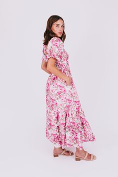 Stay light-hearted and lovely in the Rosy Outlook Dress. This tiered maxi length dress boasts a playful sweetheart neckline, puff sleeves, and a flirty ruffle on the shoulders. The floral pattern in shades of pink and green on a white background will have you feeling positively blooming. Details Smocked bodice Tiered Floral pattern with shades of pink and green on a white background Slight puff sleeve with elastic Ruffle on shoulders of neckline Sweetheart neckline Maxi length Lined on chest dow Pink Smocked Bodice Maxi Dress For Garden Party, Pink Feminine Tiered Maxi Dress, Feminine Pink Tiered Maxi Dress, Pink Maxi Dress With Smocked Back For Garden Party, Pink Tiered Maxi Dress With Smocked Back, Pink Tiered Midi Dress With Smocked Back, Pink Tiered Dress With Smocked Bodice, Flowy Pink Tiered Dress For Vacation, Pink Feminine Maxi Dress With Smocked Bodice