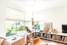 a living room filled with furniture and a dog sitting on top of a chair in front of a window