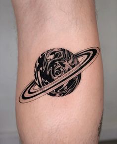 a black and white saturn tattoo on the thigh