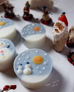 soaps decorated like santa claus and snowmen are sitting on a white tablecloth