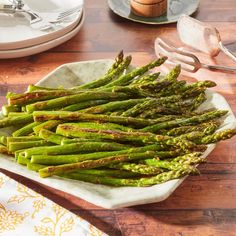 asparagus spears on a white plate next to silverware