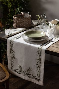 a table set with plates and napkins on it, next to a basket full of flowers