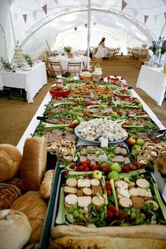 a long table filled with lots of food and bread on top of tables covered in white cloths