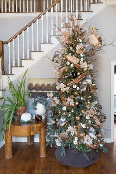 a decorated christmas tree sitting in the corner of a living room next to a stair case