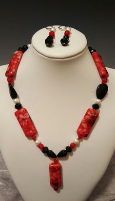 "Well, they Say the Merry Widow wore red and black and what a delightful color combination that is. This gorgeous red and black necklace with the dynamic 2 inch pendant  is definitely not for the feint of heart.   The elongated beads and pendant that are the focal point of this 22\" necklace with the 3\" extender are bold and daring. They are accompanied by red Czech crystals, white pearls and various black glass shaped beads.   The pierced hypo allergenic earrings dangle 1 ½ inches long to comp Elegant Red Beaded Necklace With Black Beads, Elegant Red And Black Beaded Necklaces, Elegant Red And Black Beaded Necklace, Red Faceted Beads Jewelry For Valentine's Day, Red Necklace With Black Beads For Gift, Red Necklace With Black Beads As Gift, Red And Black Necklace, Crystals White, Lion Earrings