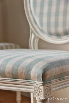 a chair with striped seat and back cushion sitting in front of a mirror on the wall