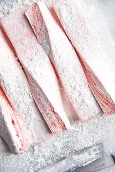 raw fish fillets sitting on top of a cutting board covered in powdered sugar