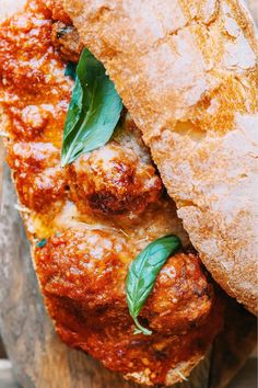 a meatball sub sandwich with basil leaves on the top and bread in the middle