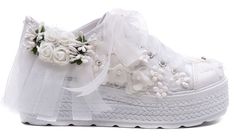 a pair of white shoes with flowers on the top and ribbons around the soles