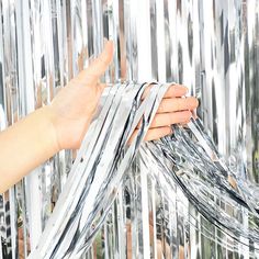 a hand is reaching for some shiny silver foil on a wall that has many wires attached to it