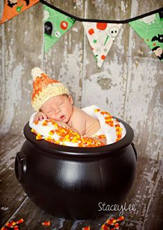 a baby is laying in a caulder with candy corn on it's side