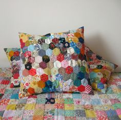 two pillows on top of a bed covered in patchwork