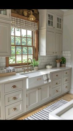 a kitchen with white cabinets and an open window above the sink is seen in this image