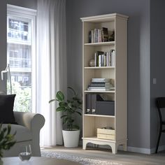 a living room filled with furniture and a book shelf in front of a large window