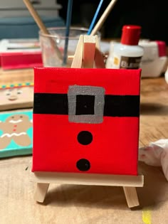 a small red box with a black and grey face on it sitting on a wooden easel