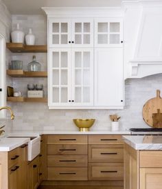 a kitchen with wooden cabinets and white counter tops, gold accents on the backsplash