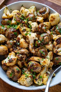 a white bowl filled with cooked mushrooms and garnished with parsley