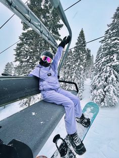 a person sitting on a ski lift with their feet up in the air while snowboarding