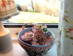 a blue bowl filled with candy next to a lamp on a window sill in front of a window