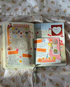 an open planner book sitting on top of a bed covered in flowers and paper hearts