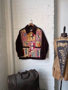 two pieces of clothing are hanging on the wall next to an old suitcase and jacket