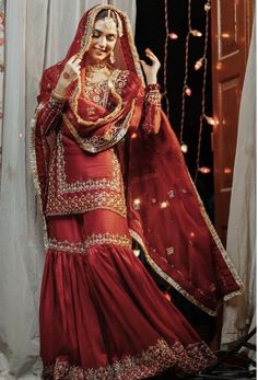 a woman dressed in red and gold is posing for the camera with her hands up