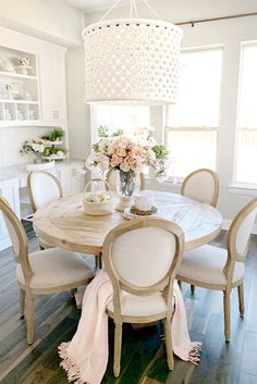 a dining room table with white chairs and a chandelier hanging from the ceiling