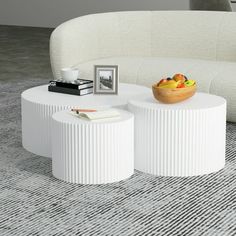 two white tables sitting on top of a carpeted floor next to a couch and coffee table