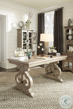 a large wooden table sitting in front of a window on top of a carpeted floor