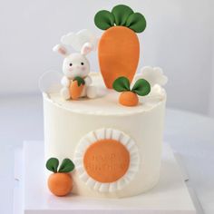 a white cake with carrots and bunny figurines on it's top