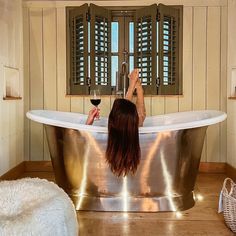 a woman sitting in a bathtub with a glass of wine next to her feet