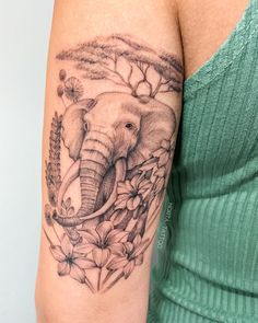 an elephant tattoo on the arm of a woman's right arm and shoulder, with flowers around it